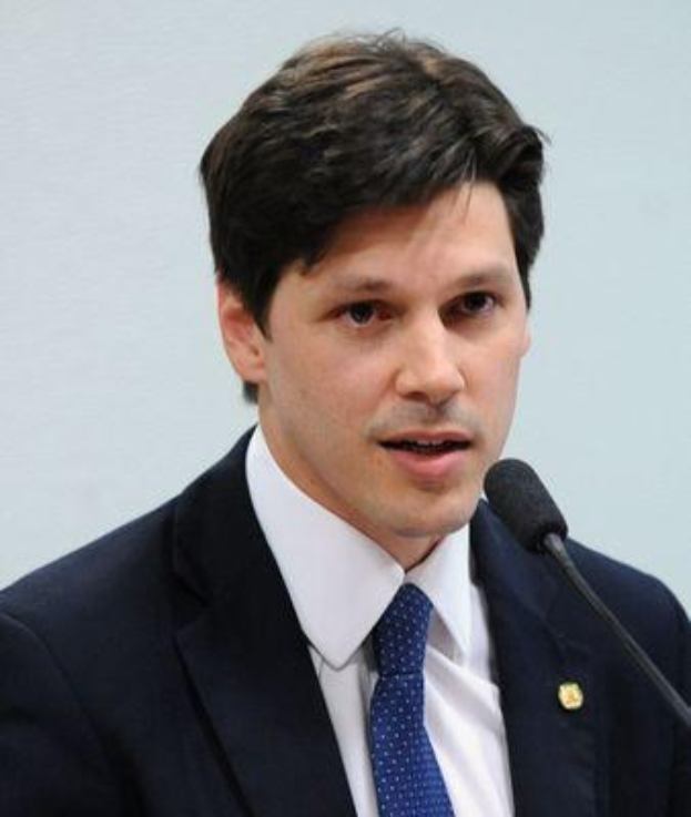 Ein Mann in Anzug und Krawatte spricht in ein Mikrofon an einem Podium, wahrscheinlich zur Genehmigung eines Gesetzes durch die Regierung.