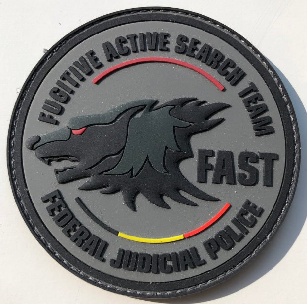 Eine weiße Fläche mit einem schwarzen kreisförmigen Logo, das einen weißen Buchstaben "F" und schwarzen Text enthält, der "Fugitive Active Search Team Fast Federal Judicial Police" lautet und in der Mitte des Kreises zentriert ist.