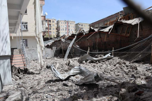 Die Auswirkungen eines israelischen Luftangriffs in Gaza-Stadt, der ein zerstörtes Gebäude mit Trümmern, eingestürzten Wänden, Metallstangen, einem Zaun, einer Treppe, nahen Gebäuden mit Fenstern, Bäumen und einem bewölkten Himmel zeigt.