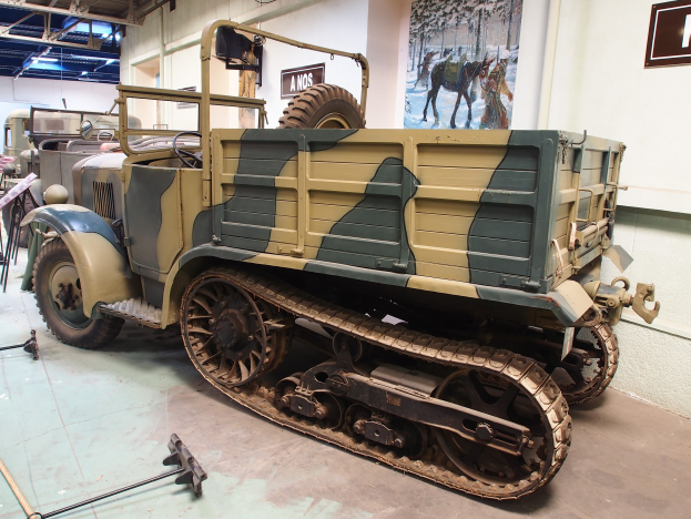 Alter militärischer M3A1-Späherwagen im Museum ausgestellt, umgeben von anderen Fahrzeugen und Informationsanzeigen.