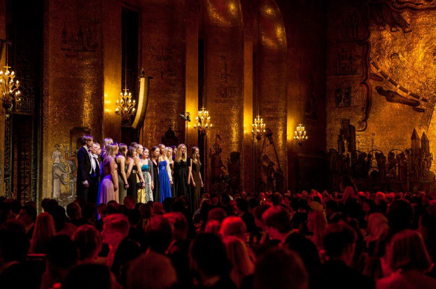 Eine Gruppe von Darstellern auf der Bühne der Royal Opera House in London, mit einem Publikum, das zusieht.