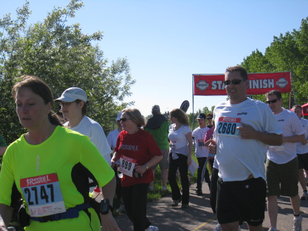 Eine Gruppe von Kindern beim Marathonlauf, mit einer roten Fahne und Bäumen im Hintergrund.