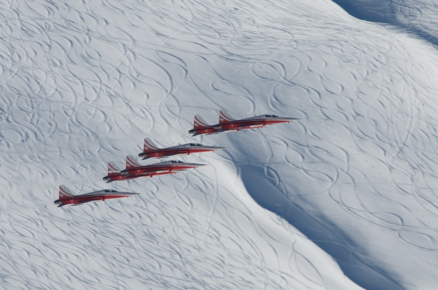 Flugzeuge in rot und weiß über einer verschneiten Landschaft.
