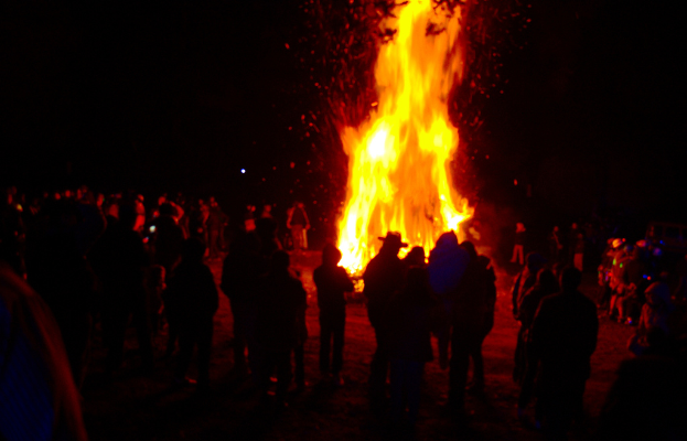 Eine Gruppe von Menschen mit einem Feuer im Hintergrund.
