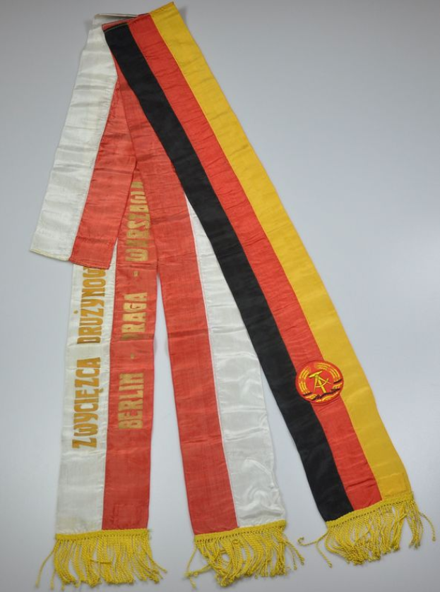 Ein roter, gelber und schwarzer gestreifter Schal mit dem Logo der deutschen Nationalmannschaft liegt auf einer weißen Oberfläche.