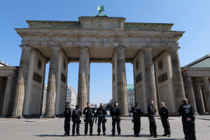 Gruppe von Polizisten vor dem Brandenburger Tor in Berlin, Deutschland, mit der Bogengestalt und Statue oben.
