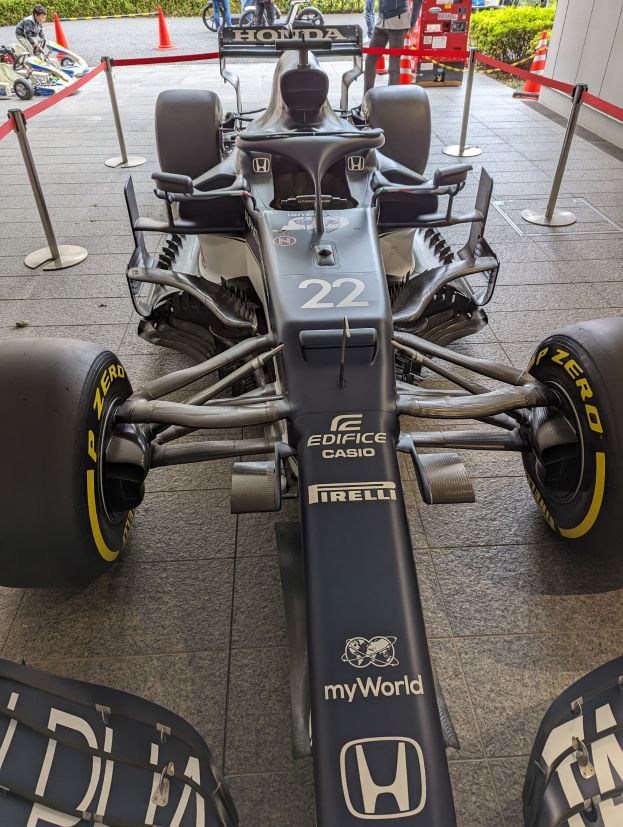 Ein McLaren Mercedes MP4-23 Formel-1-Rennwagen bei der Singapore Grand Prix, umgeben von Absperrpollern, Verkehrskegeln, Menschen, Fahrzeugen, Pflanzen, Bäumen und einem Gebäude im Hintergrund.