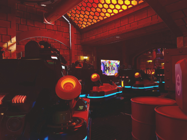 Ein hell erleuchteter Raum voller verschiedener Arcade-Videospielautomaten, Bildschirme und andere Gaming-Ausstattung.