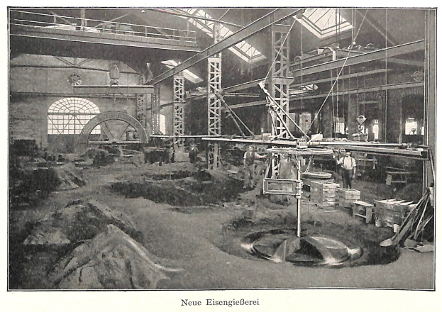 Schwarz-weißes Foto eines historischen Fabrikinneren mit Arbeitern, die an Maschinen arbeiten, umgeben von Metallstangen und - Polen, beschriftet mit "Neue Eisenglebeerei, die erste Fabrik in Deutschland" unten.