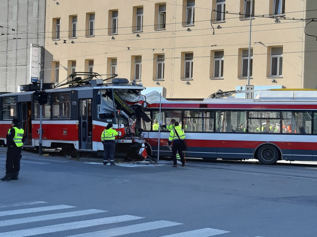 Rote und weiße Tram schlägt auf der Straße mit Menschen in der Nähe ein, Hintergrund enthält ein Gebäude.