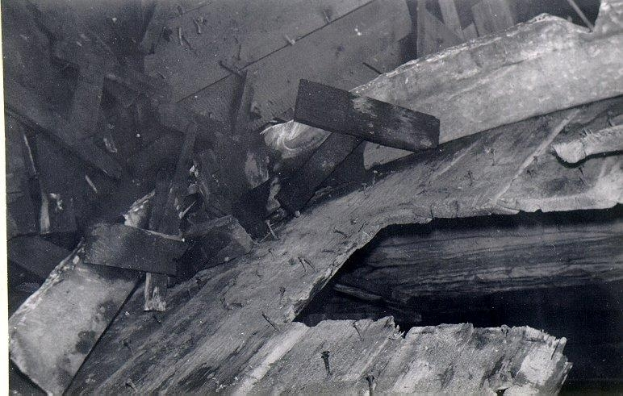 Ein Haufen unordentlicher, verkohlter Holzplanken, einige überlappend, in einem Schwarz-Weiß-Foto.