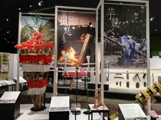 Ein Raum voller verschiedener Gegenstände, darunter Schilder mit Text, Stände und andere Objekte, mit Schildern mit Bildern und Text sowie Deckenlampen, die eine festliche Atmosphäre für die Tokyo Toy Fair 2019 schaffen.