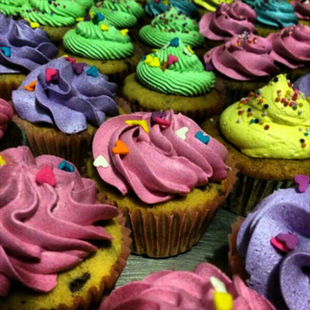 Mehrere Cupcakes in einer Reihe mit verschiedenenfarbiger Glasur.