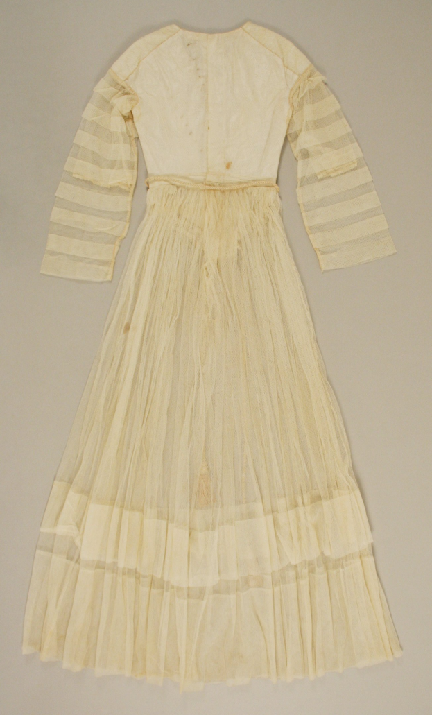 Weißes Spitzenkleid mit langen Ärmeln und einem bauschigen, gerafften Rock, der bis zum Boden reicht, auf einer weißen Oberfläche.