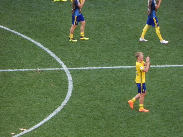 Eine Gruppe von Männern in Fußballtrikots klatscht feierlich auf einem Fußballfeld.