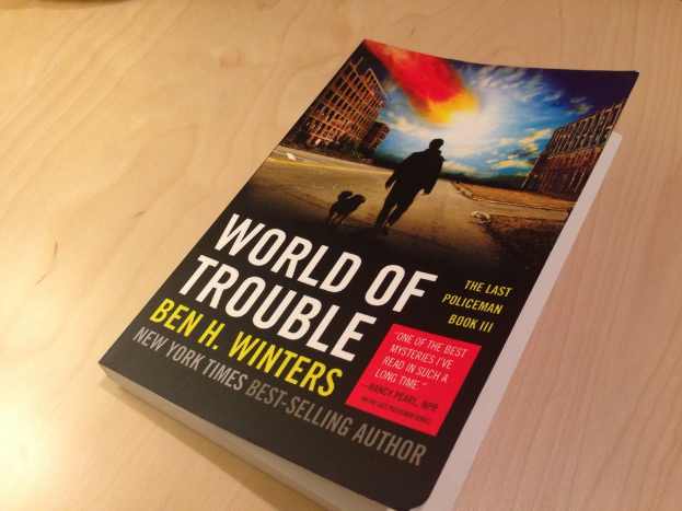 Ein Buch mit dem Titel "Welt der Probleme", das einen Mann und einen Hund auf dem Cover zeigt, liegt auf einem Tisch.