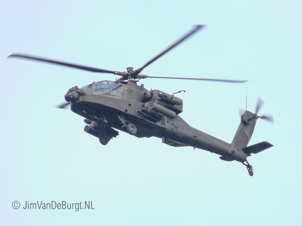 Ein militärisches Chinook-Hubschrauber fliegt mit ausgefahrenem Fahrwerk, seine beiden Rotoren drehen sich gegen einen klaren Himmel.