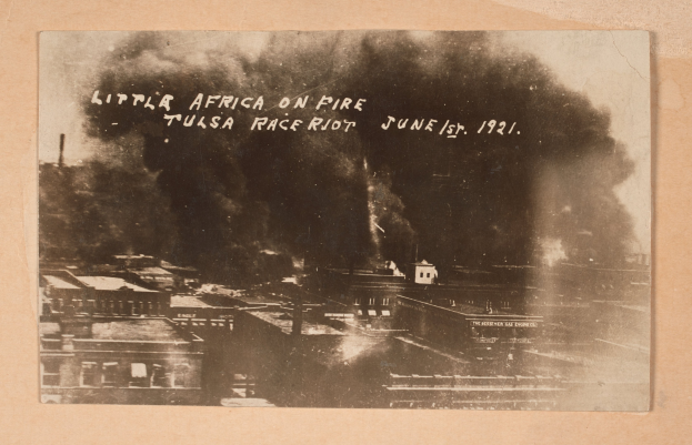 Schwarzes und weißes Foto einer Stadt mit Rauch, der daraus aufsteigt, und Text in der Mitte sowie Gebäuden unten.