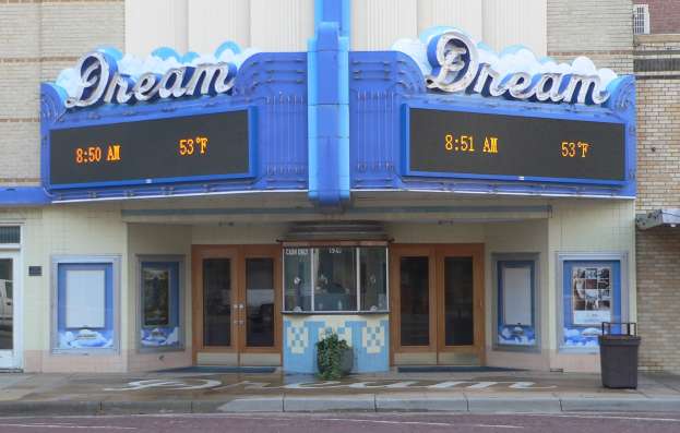 Außenansicht des Dream Theaters in St. Louis, Missouri, mit Glastüren und -fenstern, einem Namensschild, einem Müllbehälter, einem Topf mit einer Pflanze und einer Straße am Boden.