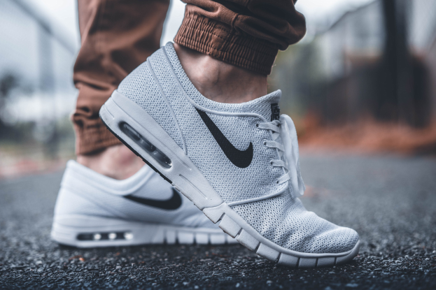 Eine Person trägt Nike SB Stefan Janoski Max Schuhe in Wolf Grau/Schwarz-Weiß mit einem unscharfen, träumerischen Hintergrund.