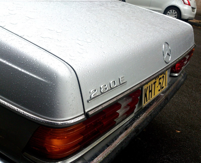 Mercedes-Benz-Logo auf einem Fahrzeug, das auf einer Straße mit einem anderen Fahrzeug nebenher fährt.
