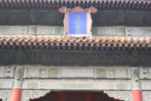 Der Eingang zur verbotenen Stadt in Peking, China, mit einem Gebäude mit detaillierten Designs, Säulen und einer Tafel mit Text.