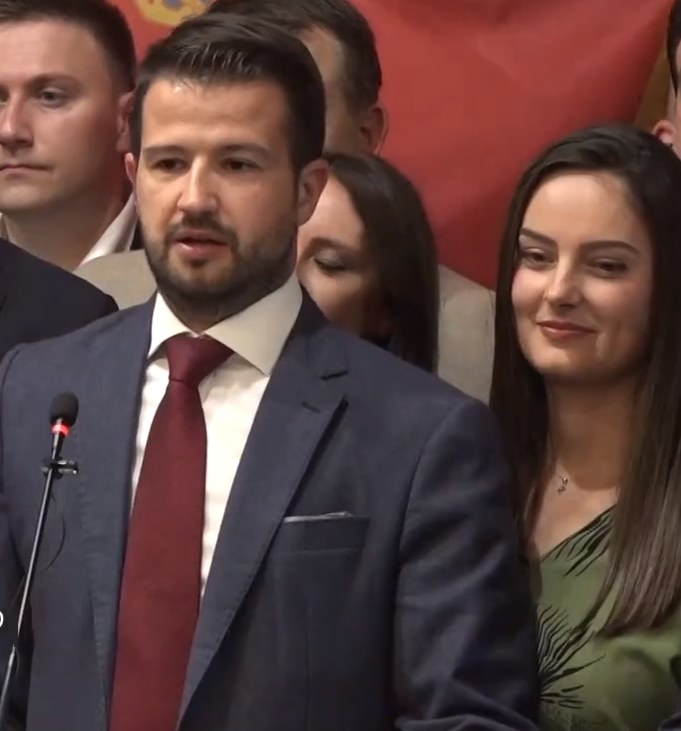 Cartoon-Panel eines Mannes in einem Zylinder, der ein Papier hält und eine Frau in einem Kleid in eine Diskussion vertieft ist.