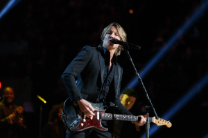 Keith Urban performs auf der Bühne im Joint im Hard Rock Hotel & Casino in Las Vegas, spielend eine Gitarre mit einem Mikrofon davor und Musikern im Hintergrund bei gedämpfter Beleuchtung.