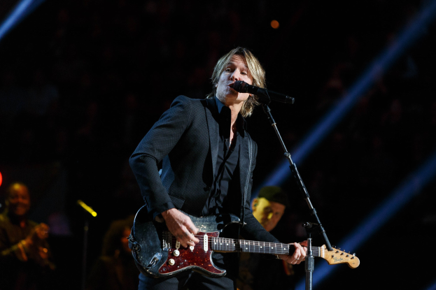 Keith Urban performs auf der Bühne im Joint im Hard Rock Hotel & Casino in Las Vegas, spielend eine Gitarre mit einem Mikrofon davor und Musikern im Hintergrund bei gedämpfter Beleuchtung.