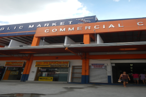 Öffentlicher Marktkomplex mit Menschen vor dem Gebäude, Text auf dem Gebäude und sichtbarem Himmel.