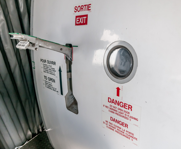 Nahaufnahme eines Metallbehälters mit Türgriff, einer "Gefahr"-Aufschrift und einem Vorhang auf der linken Seite.