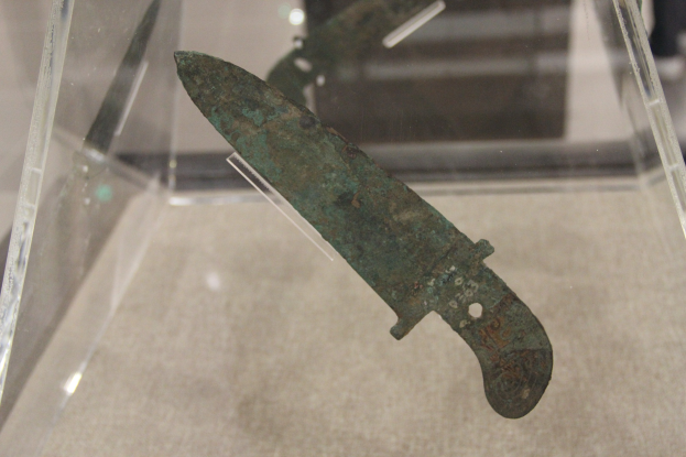 Ein Messer in einer durchsichtigen Glasvitrine, mit detaillierten Gravuren auf der Klinge.