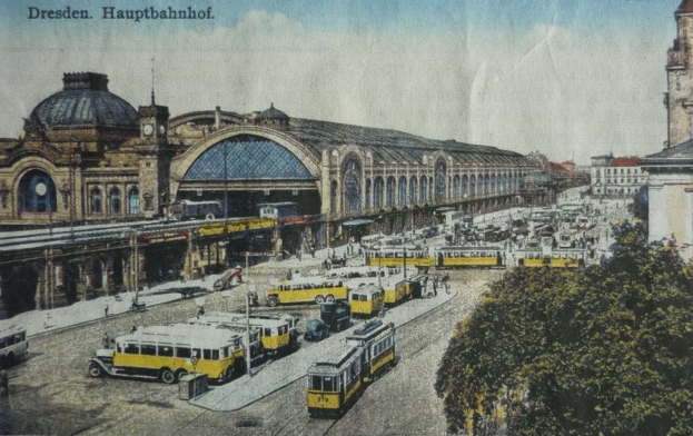 Schwarz-weiß-Postkarte des Dresdner Hauptbahnhof Bahnhofs in Deutschland, die eine belebte Straßen Szene mit Fahrzeugen, Fußgängern, Bäumen, Gebäuden und einem bewölkten Himmel zeigt.