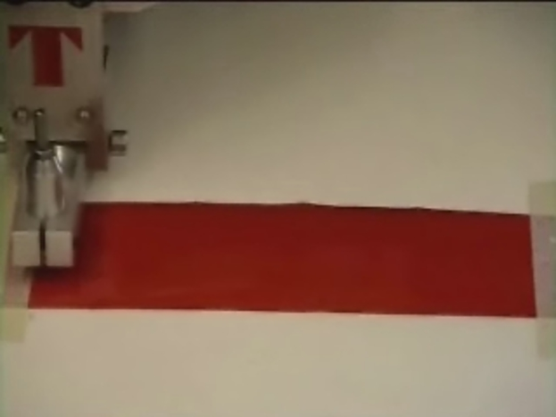 Eine Maschine ist auf der linken Seite einer weißen Oberfläche positioniert, auf der ein rotes Tuch liegt.
