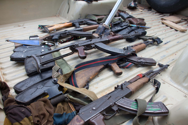 Ein Lastwagen mit verschiedenen Waffen, Taschen und anderen Gegenständen beladen, mit einem Reifen auf der rechten Seite sichtbar.