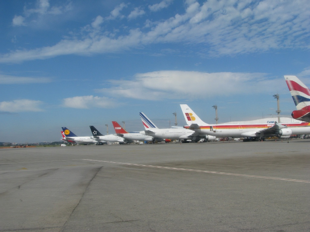 Eine Start- und Landebahn mit wenigen Flugzeugen, Pfählen, Kabeln und einer bewölkten Himmel.