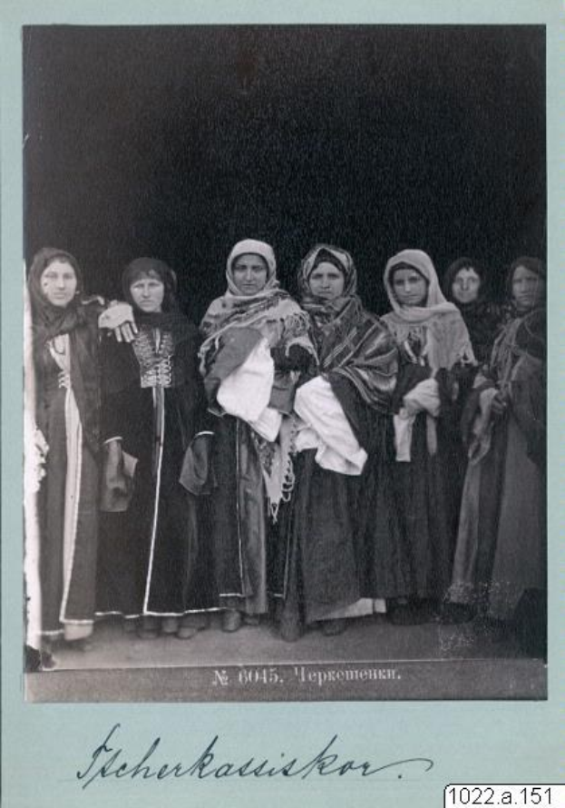 Ein Schwarz-Weiß-Foto einer Gruppe von Frauen in traditioneller russischer Kleidung mit Kopftüchern und Schmuck, die zusammenstehen und in die Kamera lächeln.