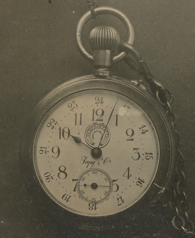 Altes Schwarz-Weiß-Foto einer Taschenuhr mit einer Kette, mit einem numerierten Zifferblatt.