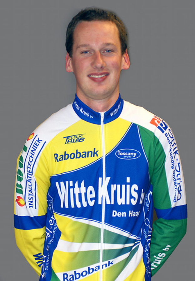 Ein Sportler posiert für ein Foto, trägt ein T-Shirt mit den Namen verschiedener Sponsoren.