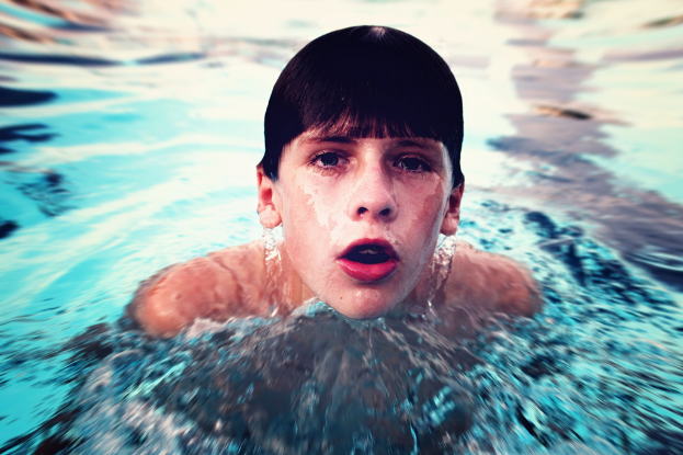 Ein Junge schwimmt in der Mitte eines Gewässers.