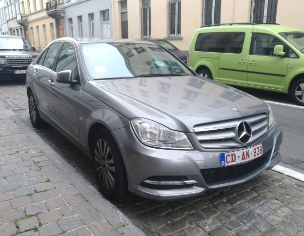 Mercedes-Benz C 220 CDI BlueEfficiency Avantgarde auf einer Straße mit Gebäuden, Fenstern, Geländern und Namenschildern im Hintergrund unter einem sichtbaren Himmel.