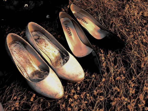 Zwei Paare Ballettschuhe, ein Paar rosa und ein Paar schwarz, sind nebeneinander auf einem Holzboden angeordnet.