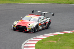 Ein Nissan GT-R Nismo GT3-Rennwagen auf der Nürburgring 24 Stunden-Strecke mit grünem Gras auf beiden Seiten.