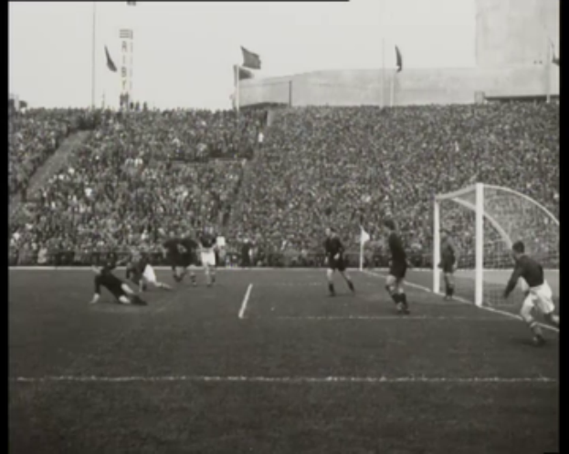 Ein Schwarz-Weiß-Foto vom WM-Finale 1958 zwischen Manchester United und Liverpool mit Spielern auf dem Feld und Zuschauern in den Rängen bei klarem Himmel.