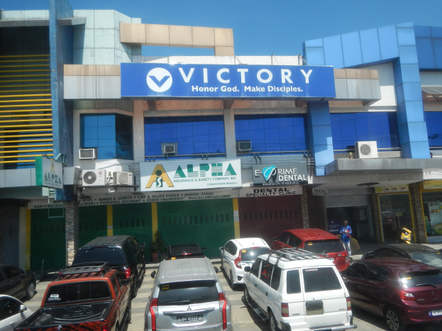 Victory Dental Clinic Gebäude in Cebu City, Philippinen, mit Fahrzeugen auf der Straße, einer Person in der Nähe und sichtbaren Texttafeln.