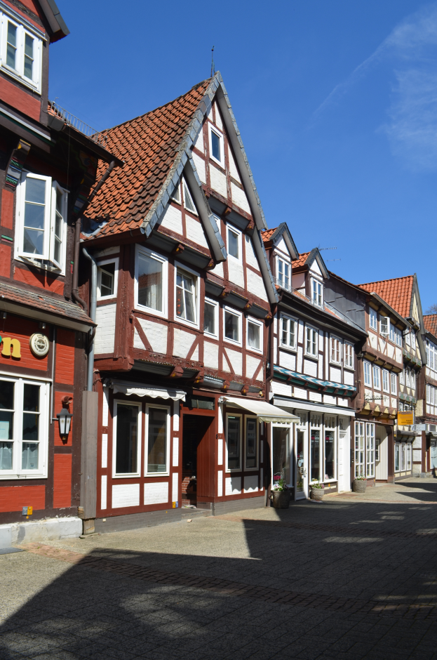 Eine Kopfsteinpflasterstraße im Alten Stadt in Heidelberg, mit Gebäuden im Vordergrund, einem klaren blauen Himmel im Hintergrund und einer Lampe, die die Straße auf der linken Seite beleuchtet.